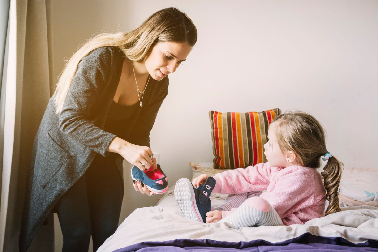 woman-assisting-her-daughter-while-wearing-shoes